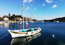 A colorful sailboat reflected in a glassy seain a